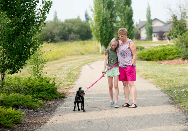 Grandmother and granddaughter with dog walking on a trail