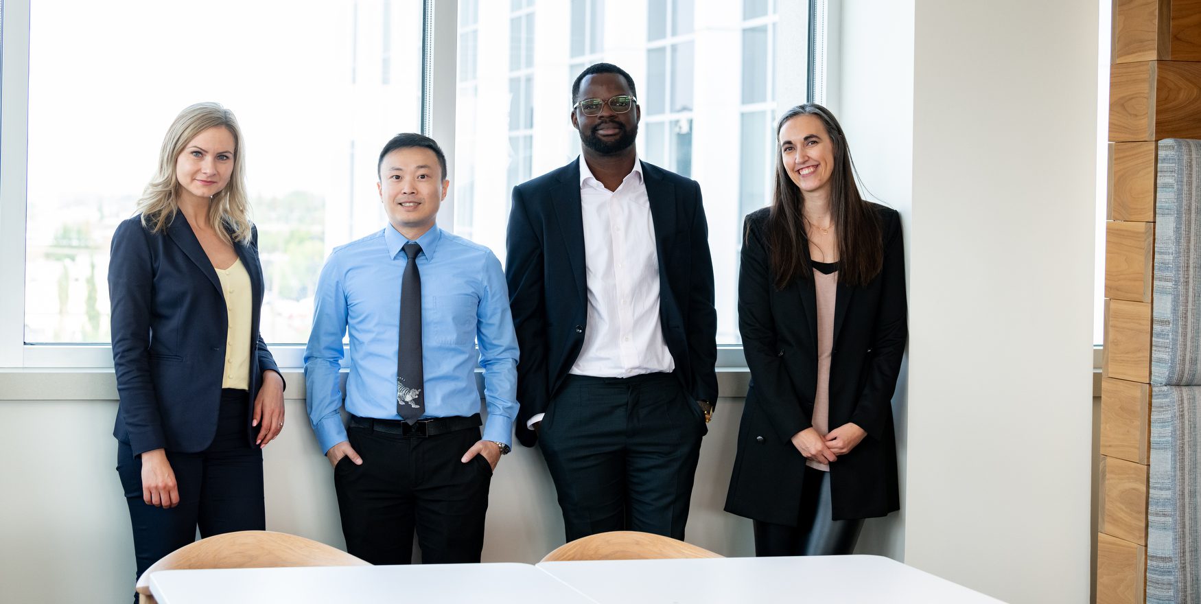 Four ATRF employees standing in front of a window, smiling at the camera.