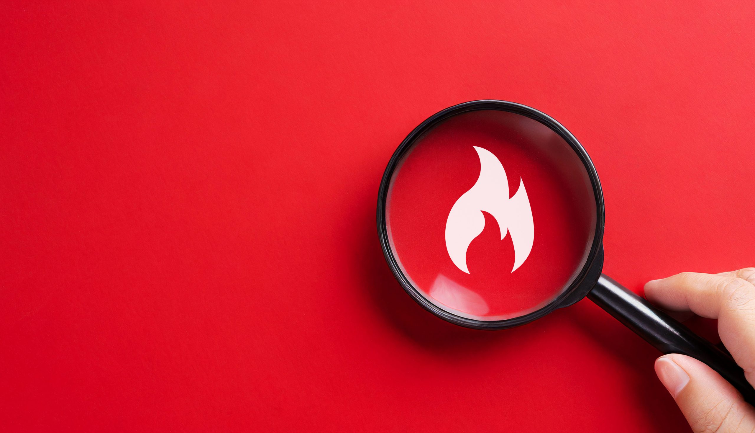 Red background with a magnifying glass focused on a white flame icon.